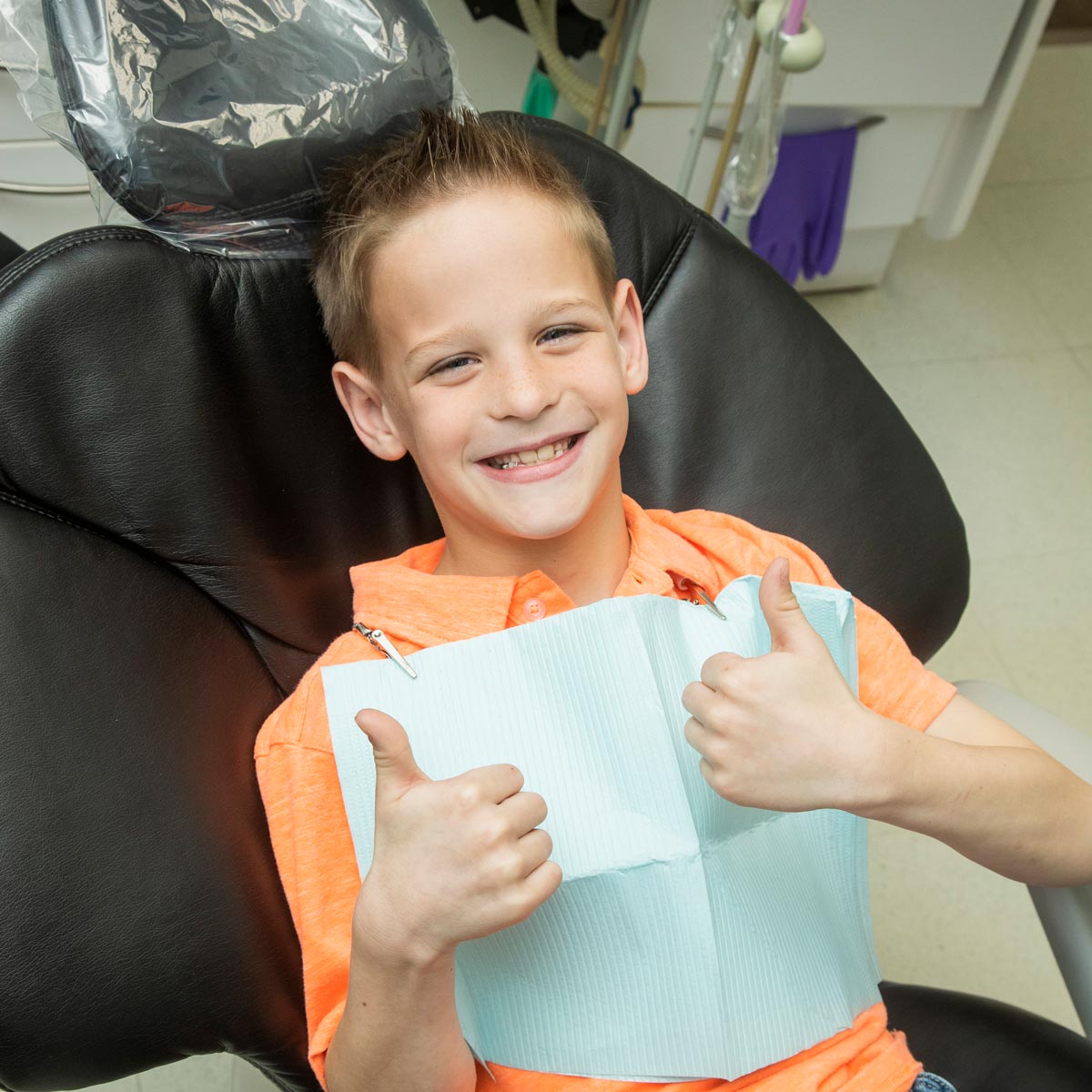 Young boy giving two thumbs up at the dentist 